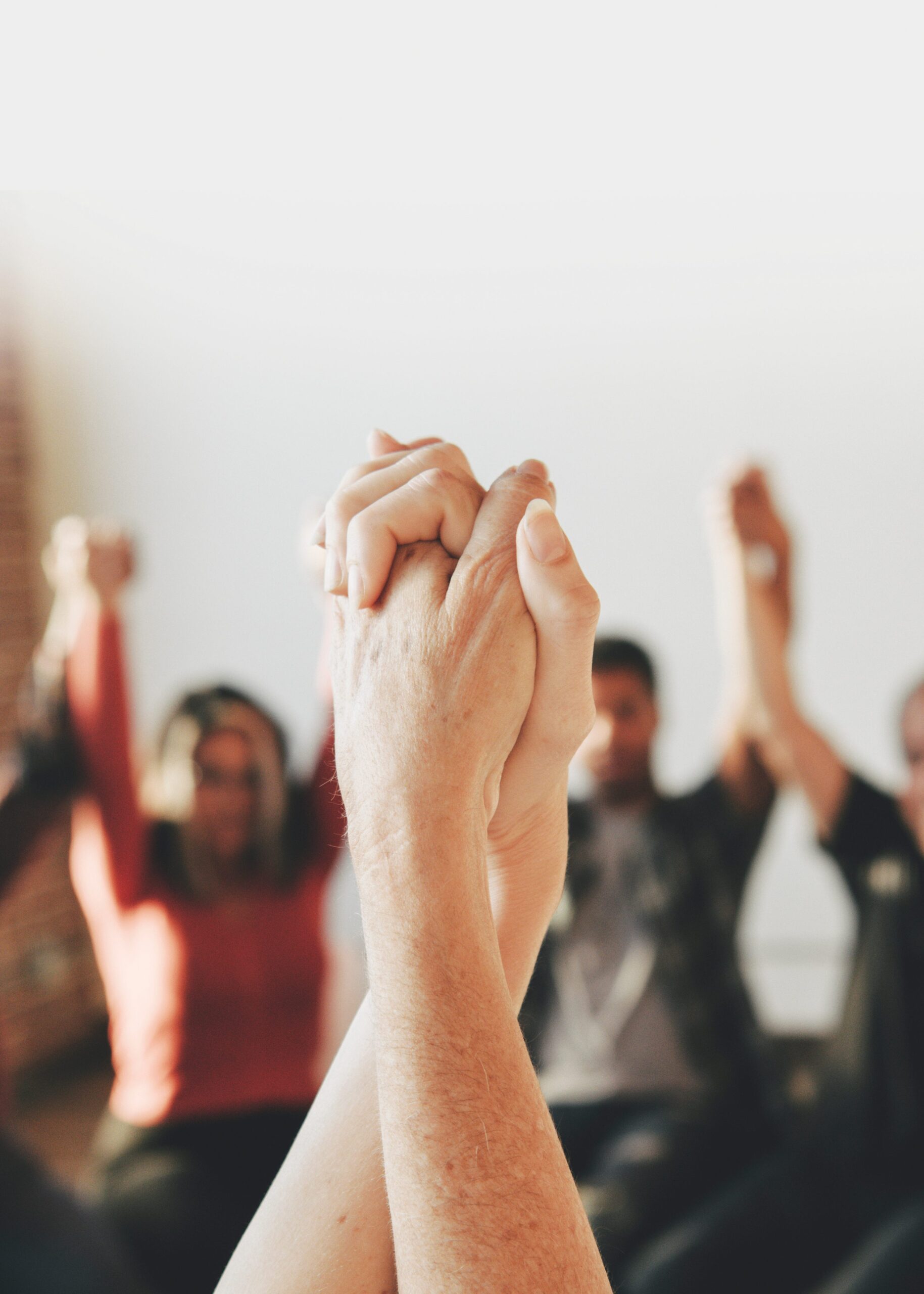 Group of diverse people holding hands up in the air